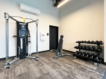 A gym with weights and cardio equipment in a corner of a room